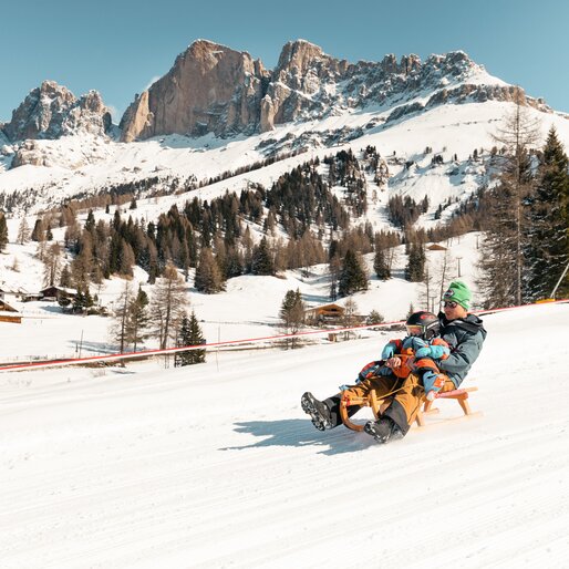 Pista da slittino Hubertus Carezza Dolomites | © StorytellerLabs Padre e figlio in slitta inverno Catinaccio | © StorytellerLabs