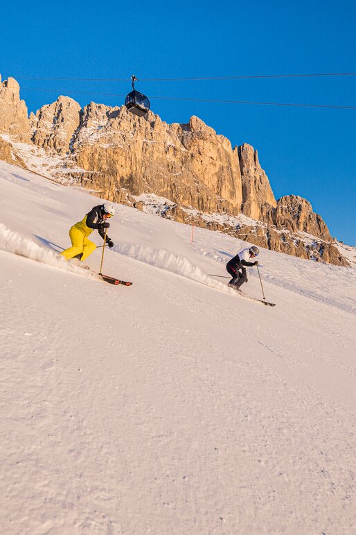 Skifahren Carezza Dolomites | © Carezza Dolomites/Harald Wisthaler Skifahrer Abfahrt König Laurin Piste - Rosengarten im Abendrot | © Carezza Dolomites/Harald Wisthaler
