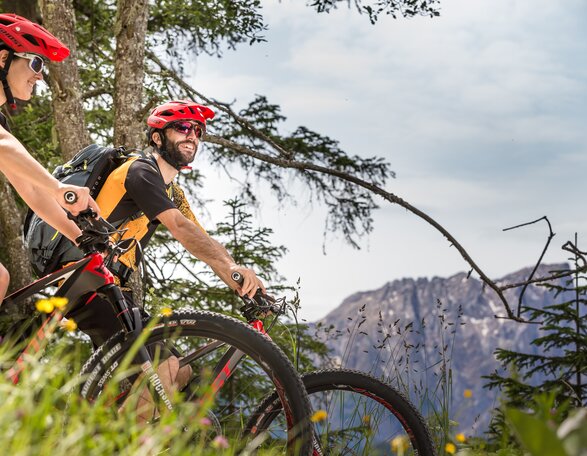 Moutainbiken in den Dolomiten | © Eggental Tourismus/Jens Staudt Mountainbiker, Wald, Blumen, Blick Latemar | © Eggental Tourismus/Jens Staudt